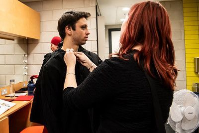 Beca Roberts adjusting a male actor's costume in the dressing room